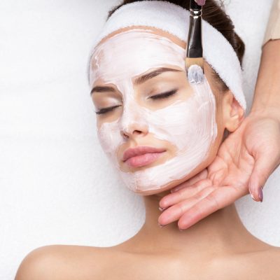Woman receiving facial mask at beauty salon